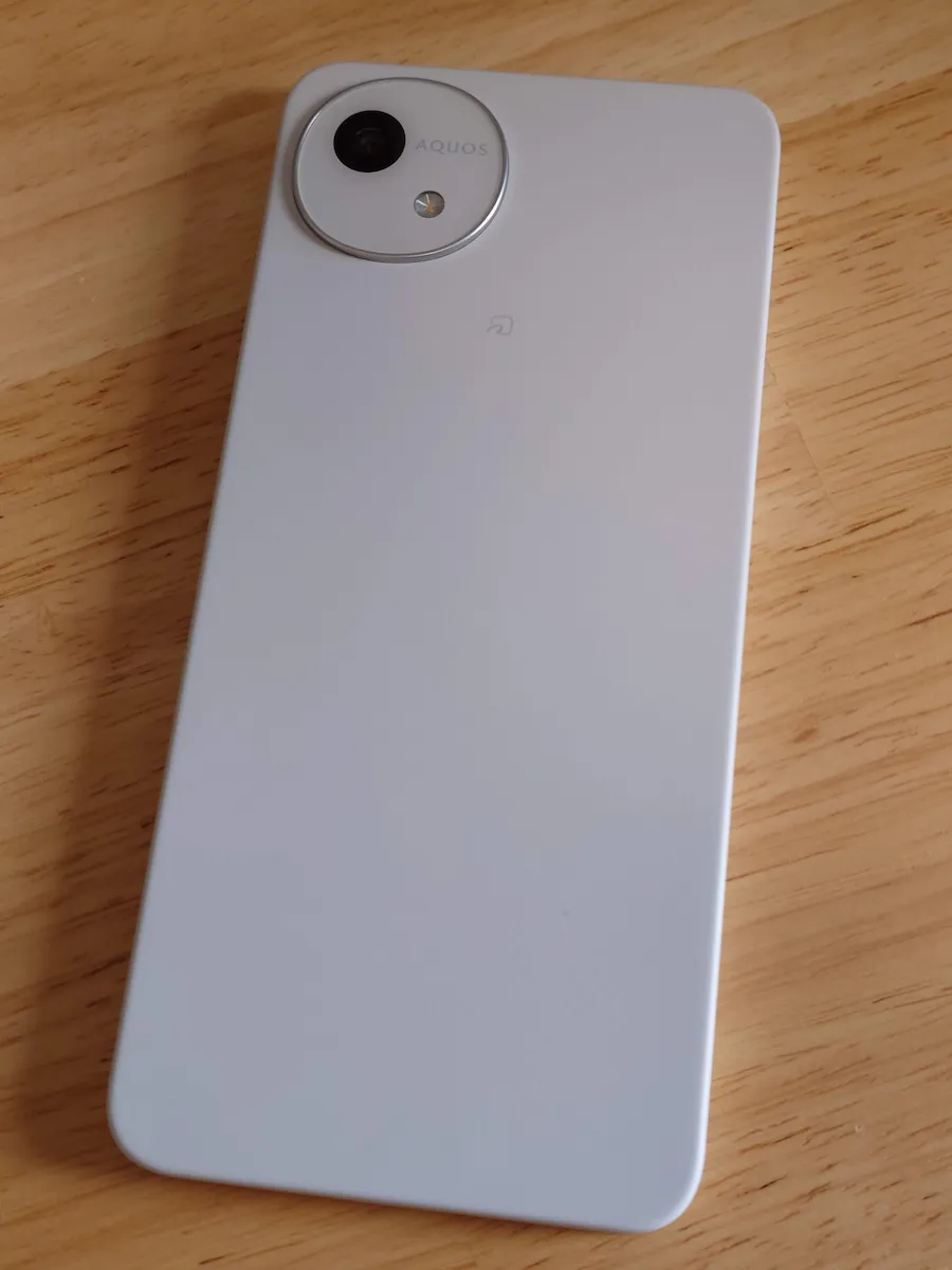 白木の机に置いたAQUOS wish5背面 実機の落ち着いた色味と優しい曲面仕上げ